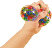 a child 's hand is holding a clear ball filled with multicolored beads