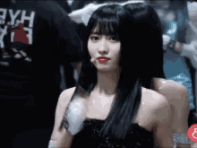 a woman in a black strapless dress with red lipstick is standing in a crowd .