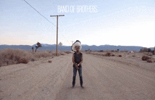 a man in a native american headdress stands on the side of a dirt road with the band of brothers written on the bottom