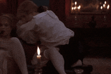 a man sits on a woman 's lap with a candle lit in the background