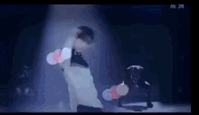 a man in a white shirt is dancing on a stage in front of a spotlight