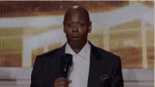 a man in a suit and tie is holding a microphone and making a face .