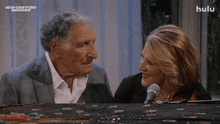 a man and a woman are looking at each other with a hulu logo behind them