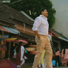 a man in a white shirt is walking down a street with a toms 2005 watermark on the bottom