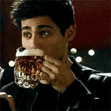 a man is drinking a beer from a large glass mug