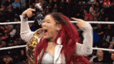 a woman with red hair is holding a microphone in a wrestling ring that says raw