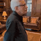 a man wearing glasses and a black shirt stands in a living room