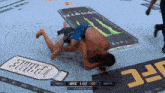 two men are wrestling in front of a monster energy drink can