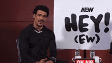 a man sits in front of an aew sign
