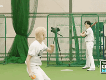a baseball player is throwing a ball while another player stands behind him