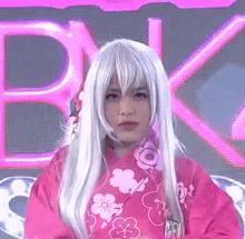 a woman wearing a pink kimono and a white wig is making a funny face .