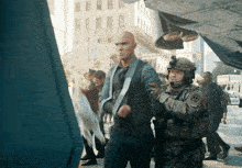 a man in a suit and tie is being escorted by a soldier with a u.s. army patch
