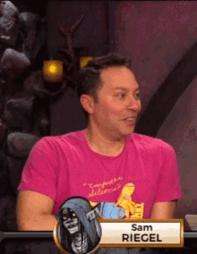 a man wearing a pink shirt with the name sam riegel