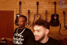 a man wearing a black shirt that says team charleston white stands next to another man