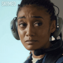 a close up of a woman wearing headphones and a headset with the word skymed written above her