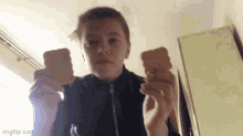 a young boy is holding two biscuits in his hands ..