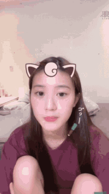 a girl with a cat ear on her head is sitting on a bed