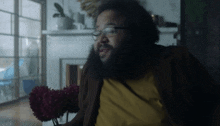 a man with glasses and a beard is sitting in front of flowers