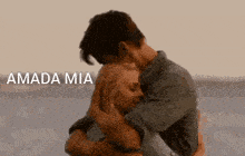 a man is holding a woman in his arms and the words amada mia are on the bottom of the picture .