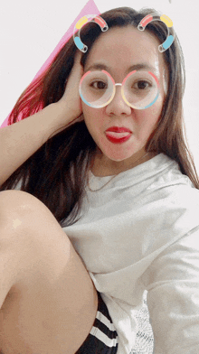 a woman wearing glasses and red lipstick makes a silly face