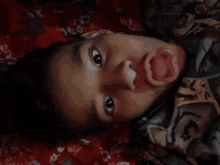 a young boy sticking his tongue out while laying on a bed