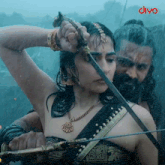 a woman holding a sword next to a man with divo written on the bottom right