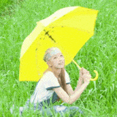 a woman is holding a yellow umbrella in the grass .