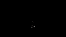 a person is standing in a dark room with a cross in the background .