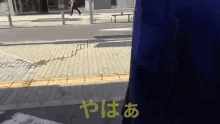 a person walking down a sidewalk with a yellow sign that says yaba