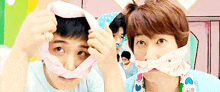 a man with a bandage around his mouth looks at the camera while another man looks on