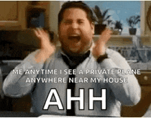 a man in a tie is screaming in a kitchen while holding his hands up in the air .