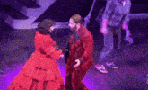 a man and a woman are dancing on a stage with purple lights .