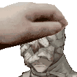 a hand is holding a statue of a man 's head with a bandage on it .
