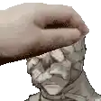 a hand is holding a statue of a man 's head with a bandage on it .