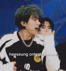 a man with green hair is wearing a black and white shirt with the word heeseung on it