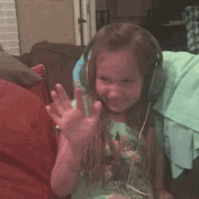 a little girl wearing headphones is covering her face