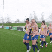 a group of female soccer players on a field with one wearing a shirt that says ' a ' on it