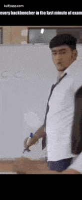 a man in a white shirt and tie is standing in front of a white board with the letter c on it .