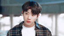 a close up of a young man wearing a plaid shirt and a bandana