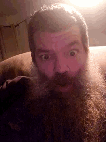 a man with a beard is laying on a couch looking at the camera