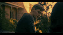 a man in a black shirt looks at a woman in a dark room