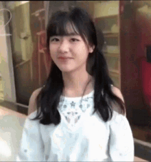 a girl with pigtails is wearing a white off the shoulder top .