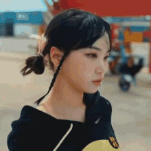 a girl with braids in her hair is wearing a black hoodie and a yellow shirt .