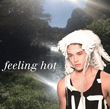a man wearing a white feathered hat stands in front of a river with the words feeling hot below him