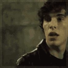 a close up of a young man 's face with his mouth open and his teeth visible .