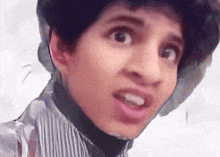a young man is making a funny face with his mouth open and his eyes closed .