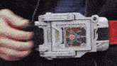 a person is holding a toy that looks like a watch with a heart on it .