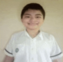 a blurry picture of a young boy in a white shirt smiling .