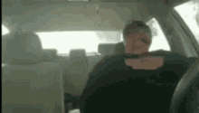 a man is sitting in the driver 's seat of a car with his head on the steering wheel .