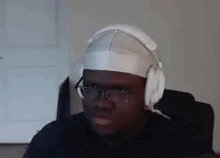 a man wearing headphones and a bandage on his head is looking at the camera .